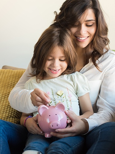 Mother and daughter putting change in piggy bank