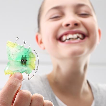 Laughing young girl holding her retainer