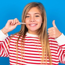 Teen shows off clear aligner while making a thumbs-up gesture