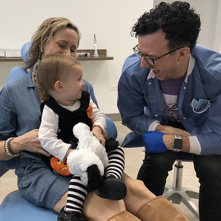 Dr. Justin laughing with mom and baby