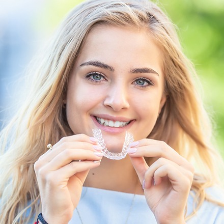 woman holding an Invisalign clear aligner