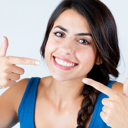 woman smiling and pointing at her smile
