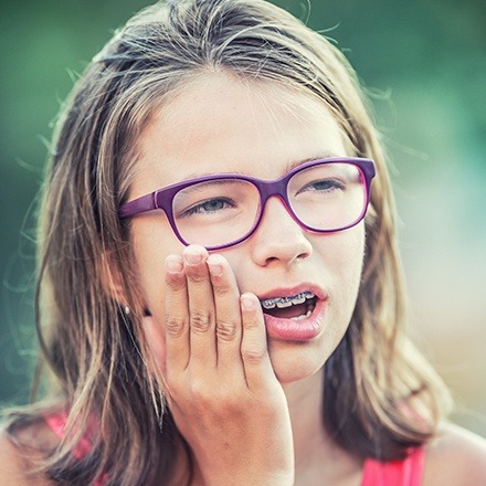 Young girl with braces holding jaw