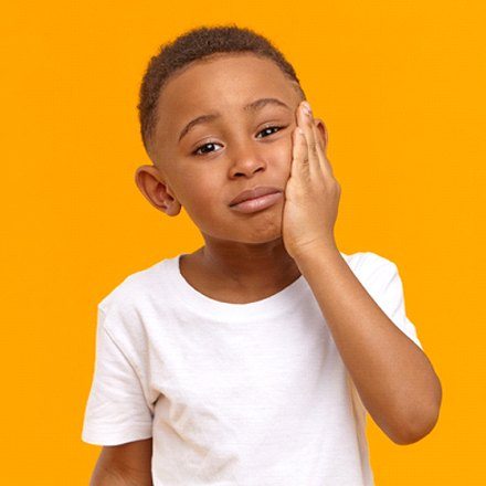 child holding his face with a dental emergency in Chicago