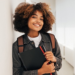 Student with backpack smiling in hallway