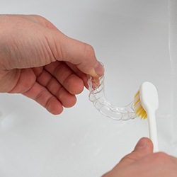 Closeup of patient cleaning clear aligner