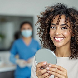 Woman smiling while holding small mirror