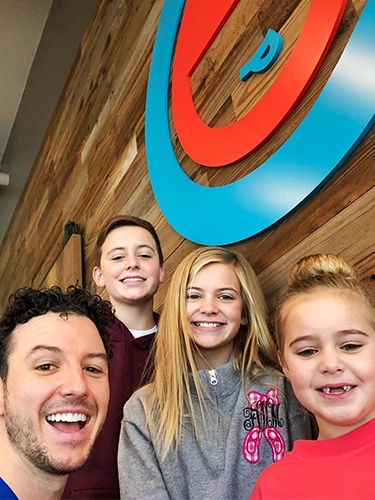 Dr. Justin smiling with a group of young patients