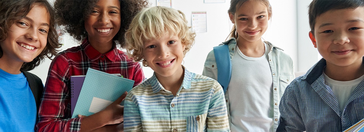 A group of smiling children holds books, showcasing their bright smiles in a dentistry and smile gallery context.