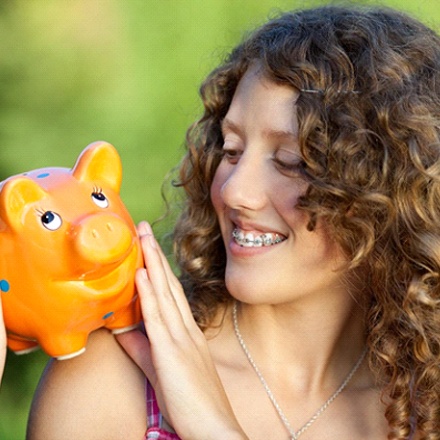 girl holding a piggy bank understanding the cost of traditional braces