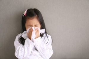 a child blowing their nose because they have a cold