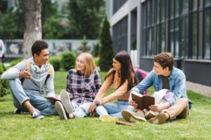 teens sitting in the grass talking to each other