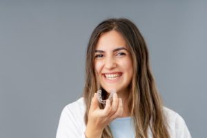 woman holding a clear aligner after taking it out