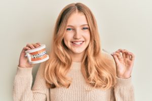 a person holding braces in one hand and aligners in the other