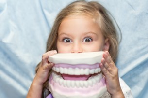 child holding large model of teeth