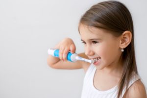 Happy girl using electric toothbrush