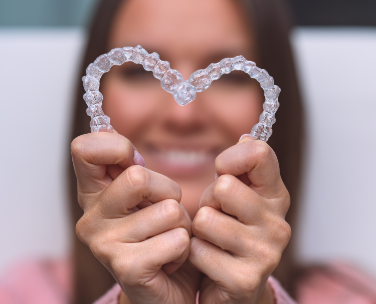 Woman holding clear aligners in heart shape